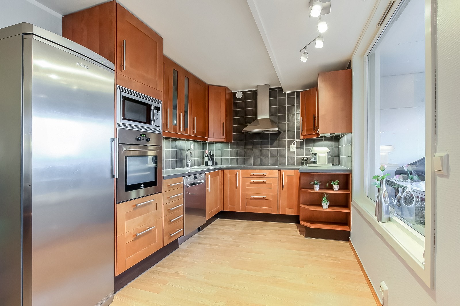 Praktisk kjøkken med godt med skap- og benkeplass - stort vindu mot balkong Galleribilde