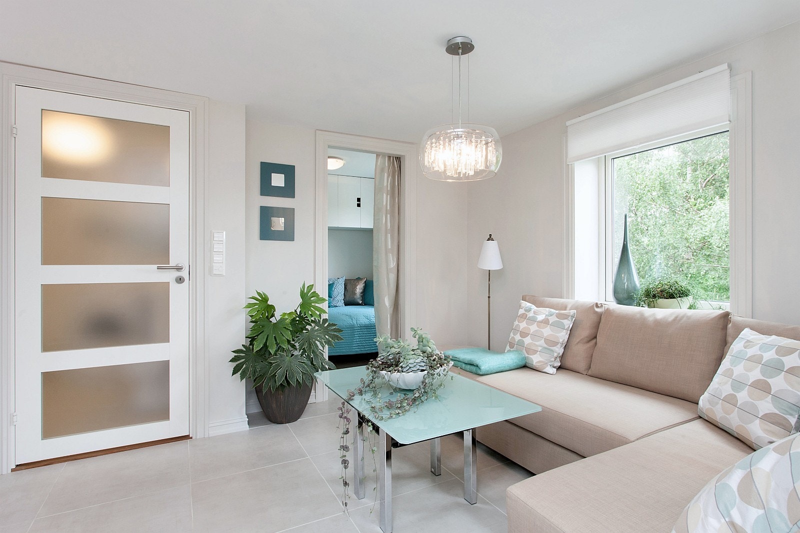 Stue med dør til bad og sovealkove og vindusutsikt til skog Galleribilde