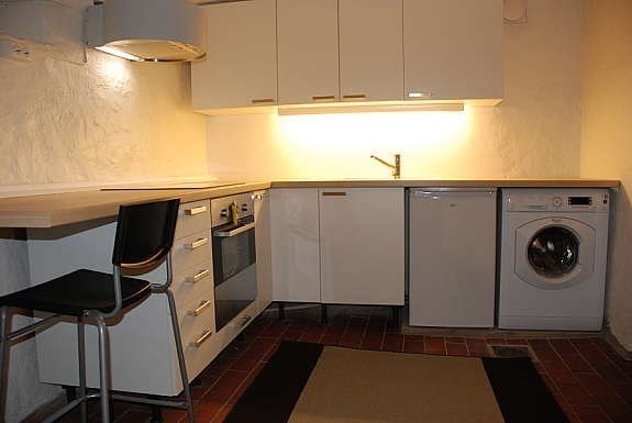 Åpen kjøkkenløsning med induksjonskomfyr, kjøleskap, vaskemaskin Galleribilde