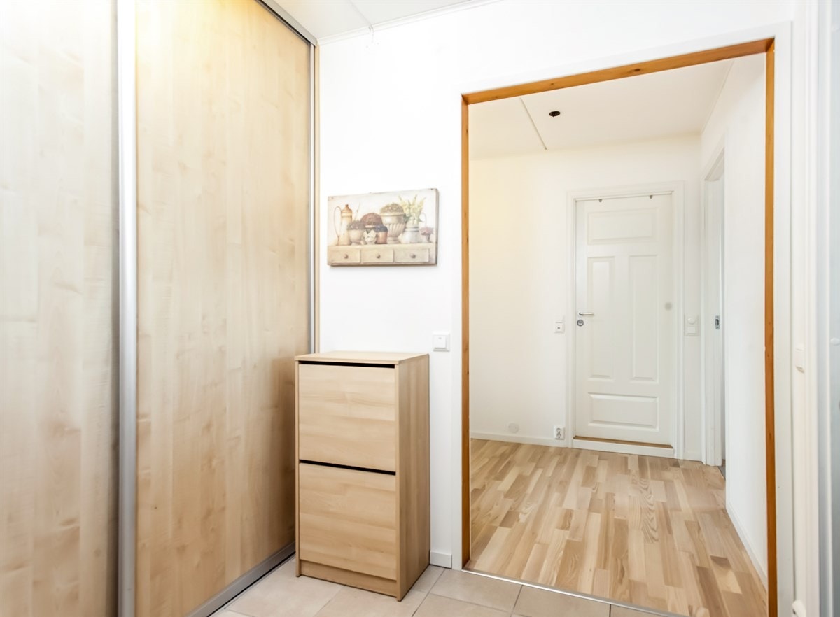 Flislagt entrè med inngang til stor garderobe med skyvedører Galleribilde