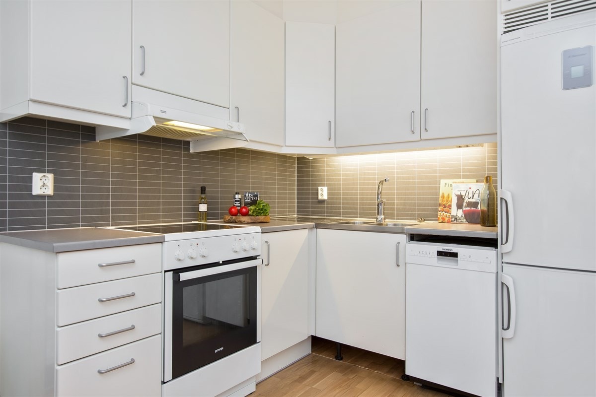 Dette er moderne og lekkert. Innredningen er lys og har matte fronter, med god plass i over- og underskap. Kontrastgivende skille mellom benkeplate og overskap. I dag står det blant annet oppvaskmaskin, komfyr med steketopp samt kjøleskap på kjøkkenet. Galleribilde