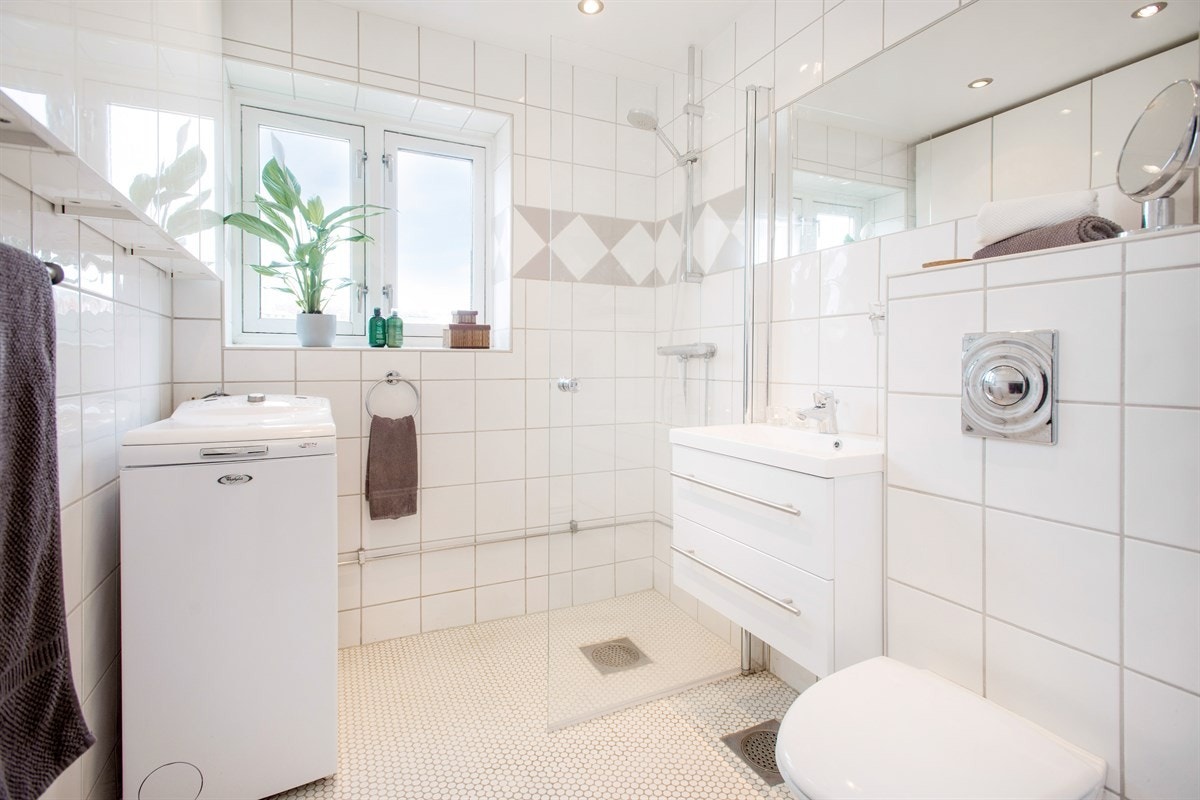 Flislagt bad med varmekabler og opplegg for vaskemaskin. Vindu som gir fint naturlig lys på badet. Galleribilde