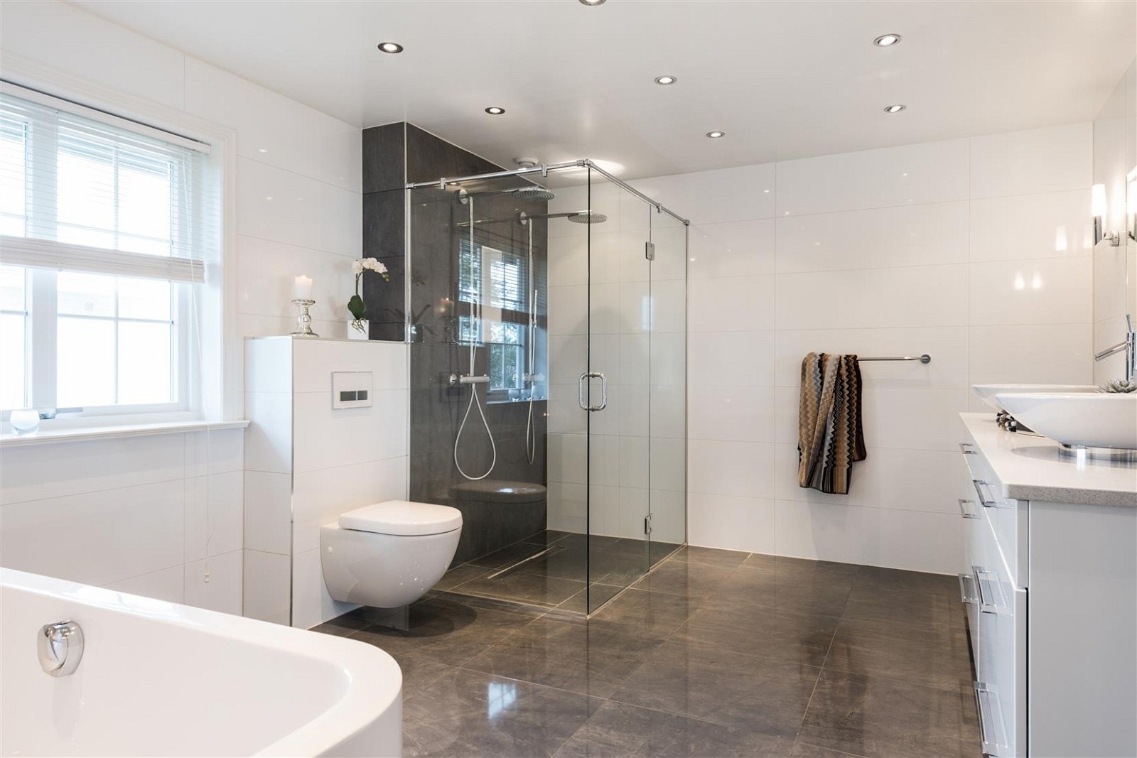 Fliser med diskre detaljer, badekar med terapilys fra Duravit. Dobbel dusj, med waterfall. Galleribilde
