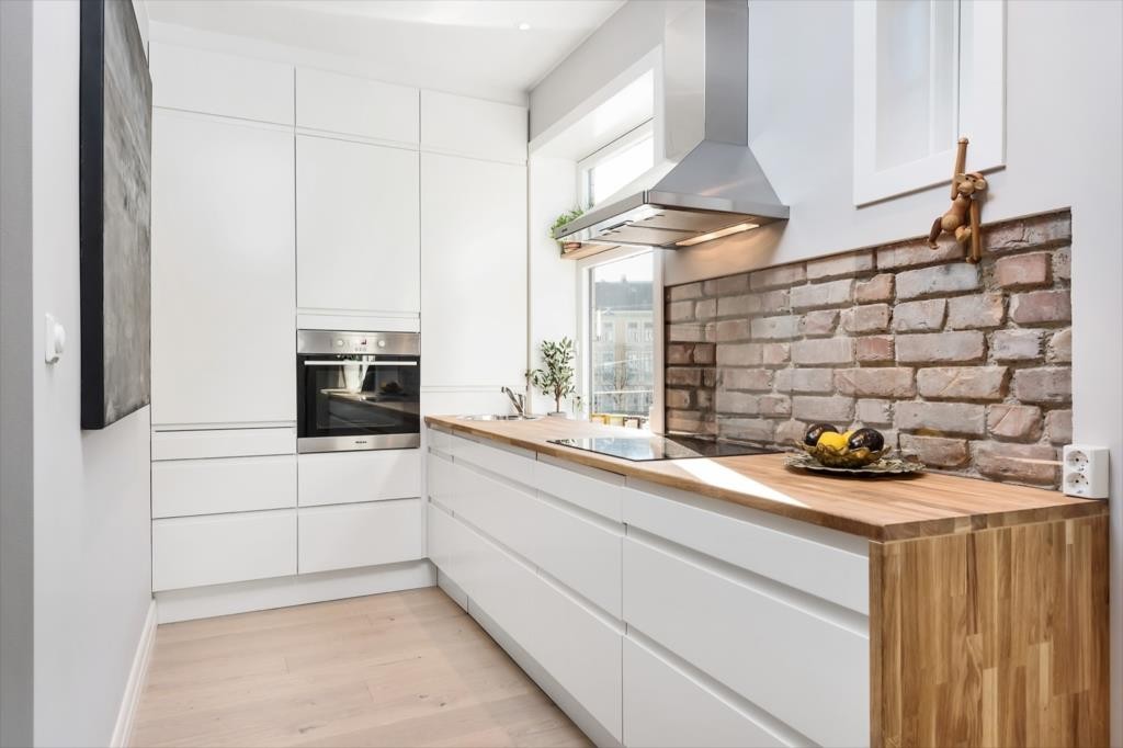 Nytt og moderne kjøkken fra HTH i 2015 med glatte fronter med integrert grep og oljet heltre eik benkeplate. Integrerte hvitevarer. Galleribilde