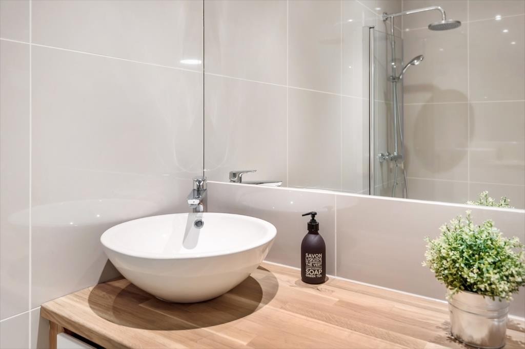 Nytt og delikat baderom med pen porelensvask over heltre eik benkeplate. Galleribilde