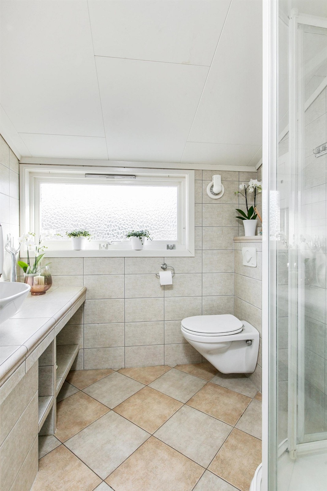 Fliser med varmekabler på gulv, fliser på veggene og takess med downlights i himling. Galleribilde