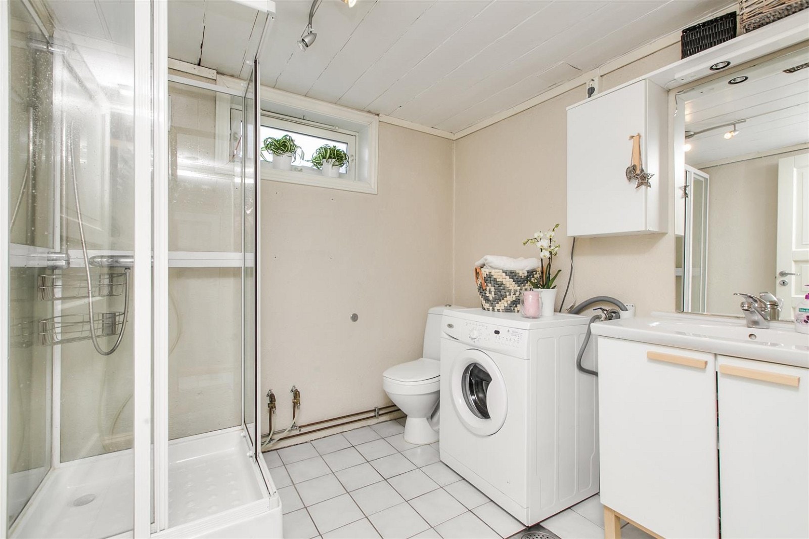 Badet i kjelleren inneholder servant med skaper, dusjkabinett, toalett og opplegg for vaskemaskin. Galleribilde