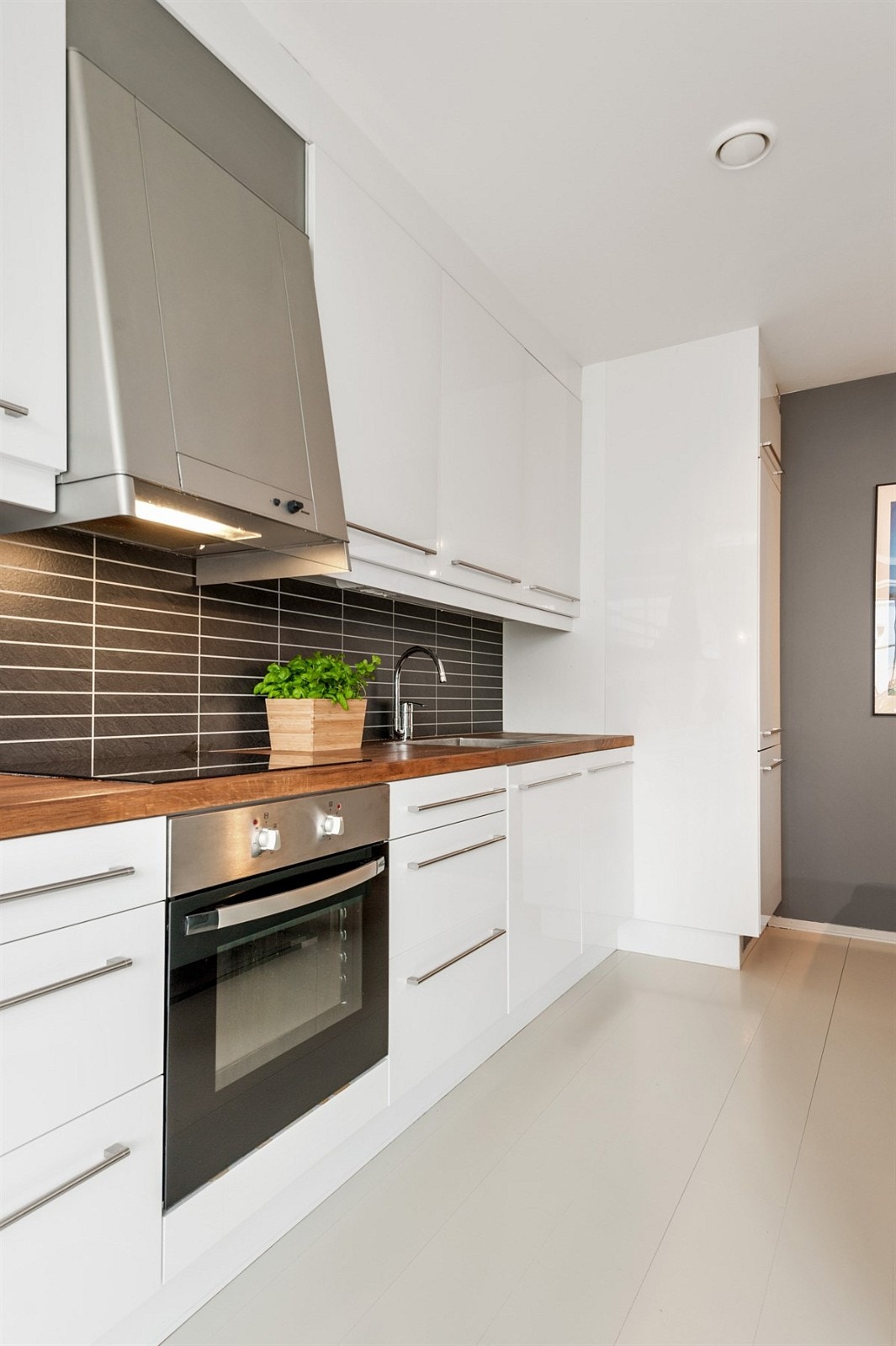 Her får du pene, lyse fronter, med stålhåndtak og integrerte hvitevarer, komfyr/steketopp samt oppvaskmaskin. Benkeplaten er i heltre eik og gir kjøkkenet et moderne og flott uttrykk. Galleribilde