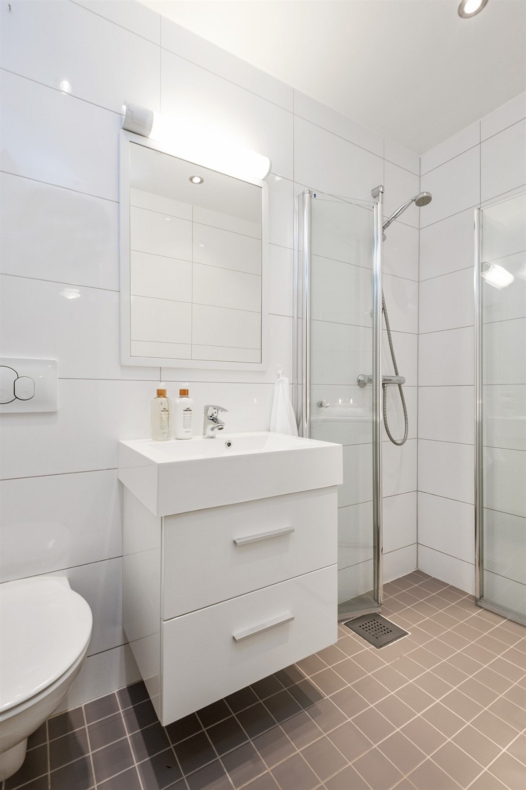 Dusjen er praktisk adskilt fra vaskemaskinen med svingbare dører i glass. Vegghengt WC. Det er opplegg til vaskemaskin. Galleribilde