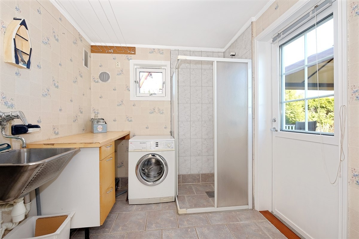 Praktisk vaskerom/grovkjøkken i bakkant av kjøkkenet. Her det både dusj og utgang til terrasse/have. Galleribilde