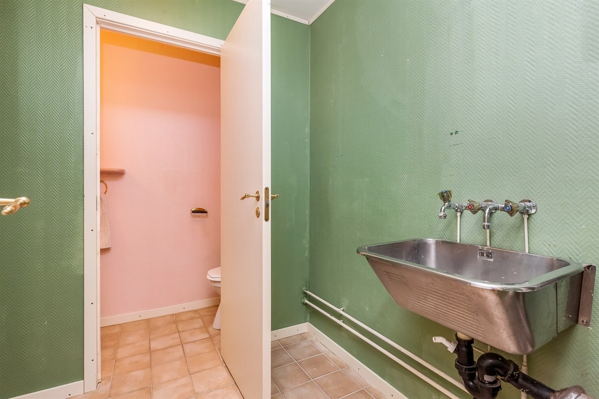 Praktisk vaskerom med utslagsvask og inngang til separat wc Galleribilde