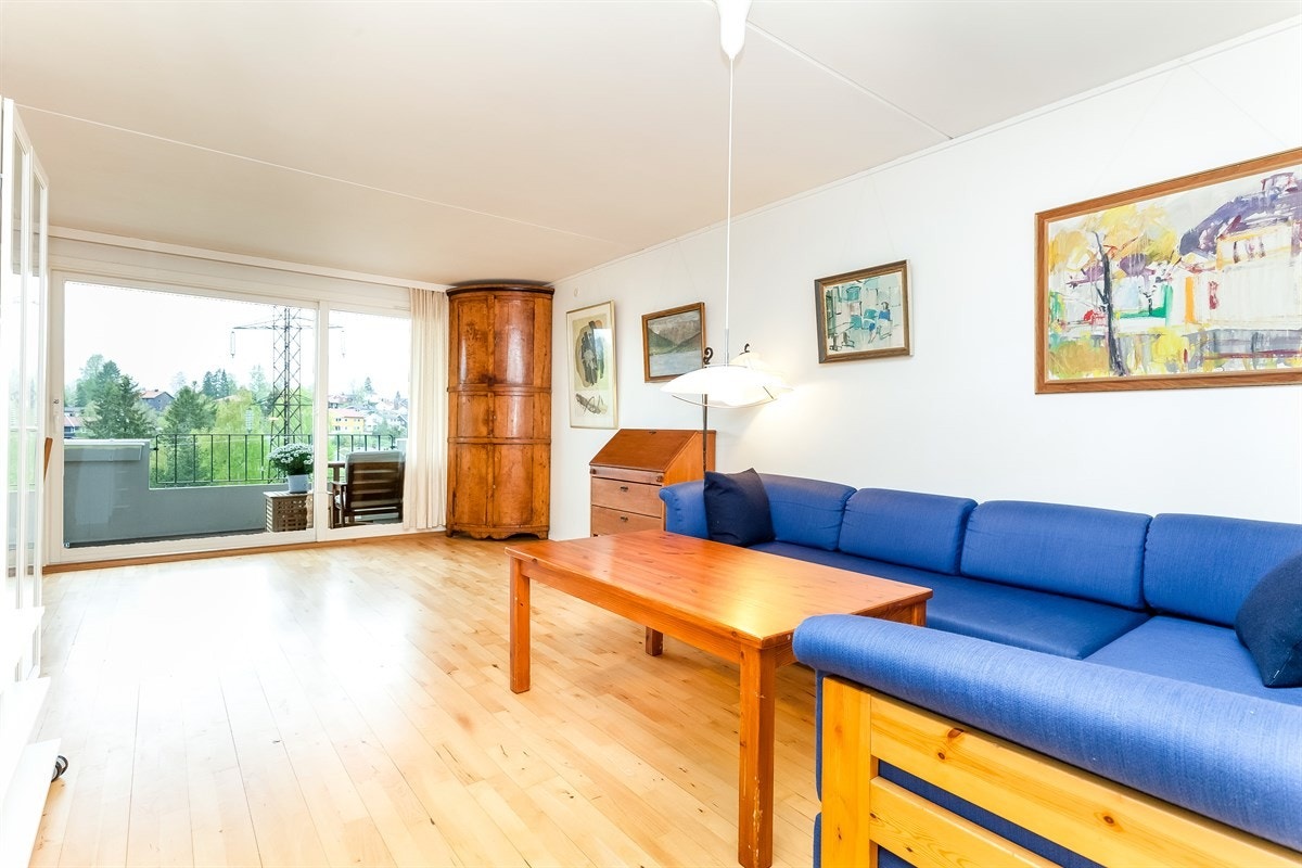 Lys og fin stue med store vindusflater og skyvedør mot balkong. Galleribilde