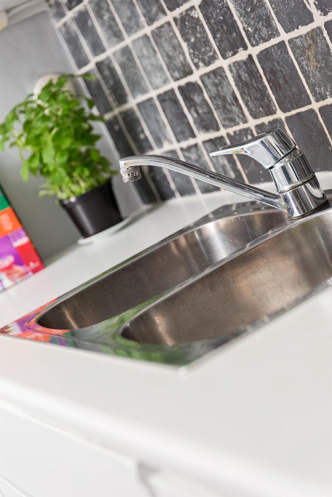 Fint kjøkken med vask med to kummer. Fliser over benk. Galleribilde