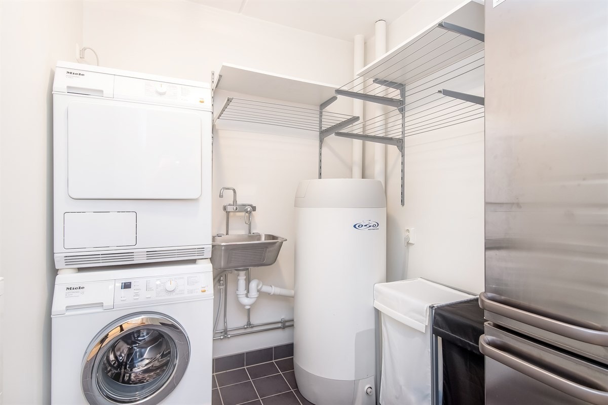 Separat flislagt vaskerom med plass for vaskmaskin og tørketrommel. Galleribilde