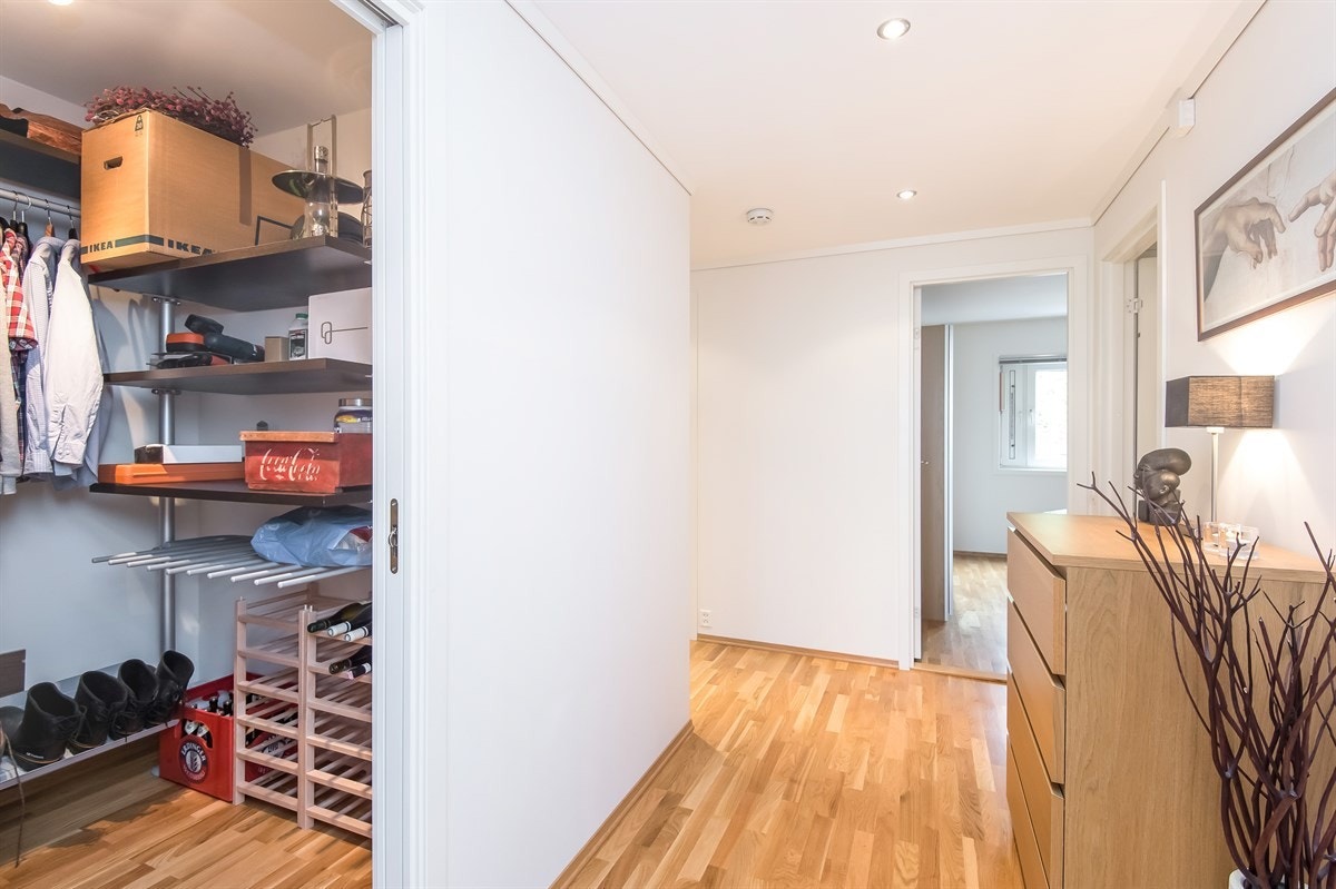Leiligheten ønsker velkommen med en lys og innbydende entre. Downlights i himling. Inngang til praktisk og romslig walk-in garderobe med hyllesystem. Galleribilde