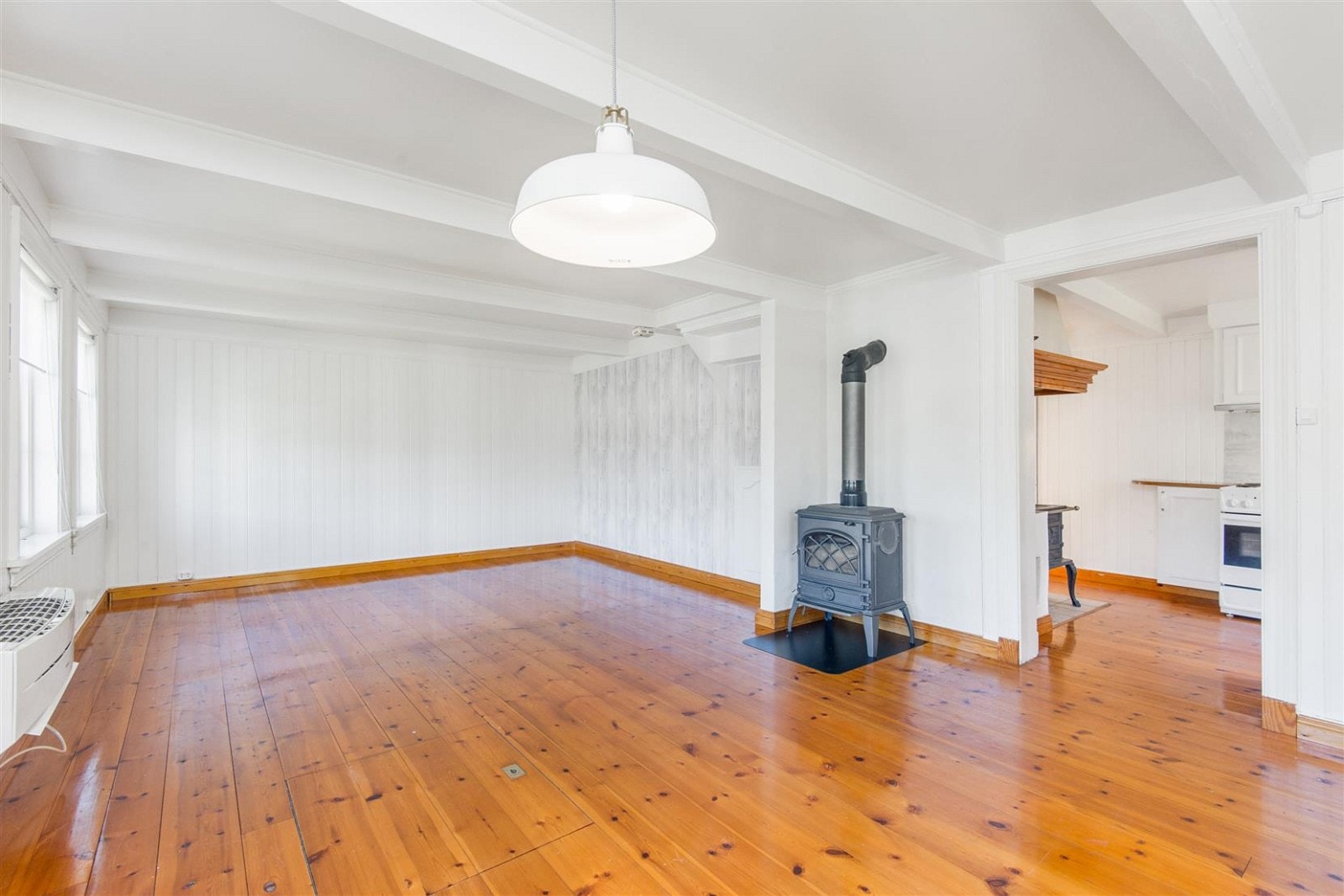 Nyere oppusset stue med lakkerte furugulv og åpne takbjelker. Galleribilde