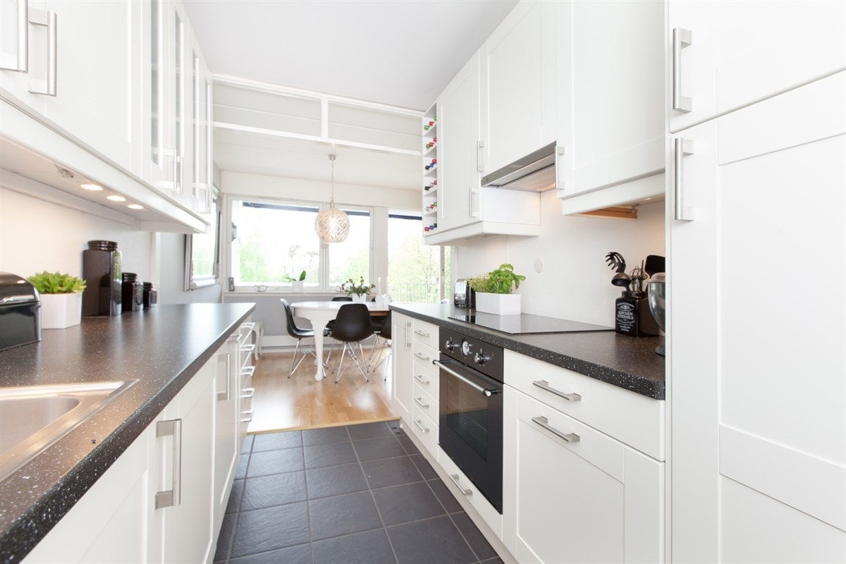 Kjøkkenet er innbydende og moderne, samt praktisk designet med god benke- og lagringsplass. Det har en lekker hvit innredning fra Ikea med hvite rammefronter, vitrineskap, vinhylle, benkebelysning og laminert benkeplate med enkel vaskekum. Galleribilde