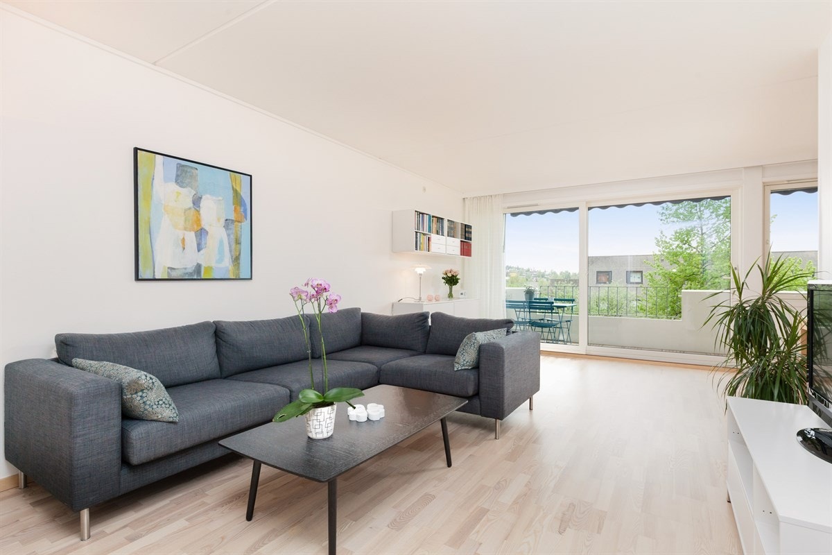 Lys og innbydende stue med glatte overflater, flott parkett i ask, store lysflater og skyvedør ut mot veranda Galleribilde