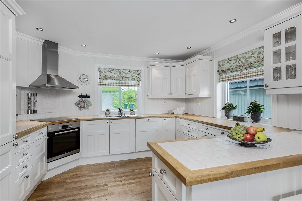 Kjøkkenet har benkebelysning, lyse fliser over kokesone, stekeovn, induksjonstopp, mikrobølgeovn, integrert kjøleskap, fryseskap, oppvaskmaskin og fritthengende ventilator i børstet stål. Galleribilde