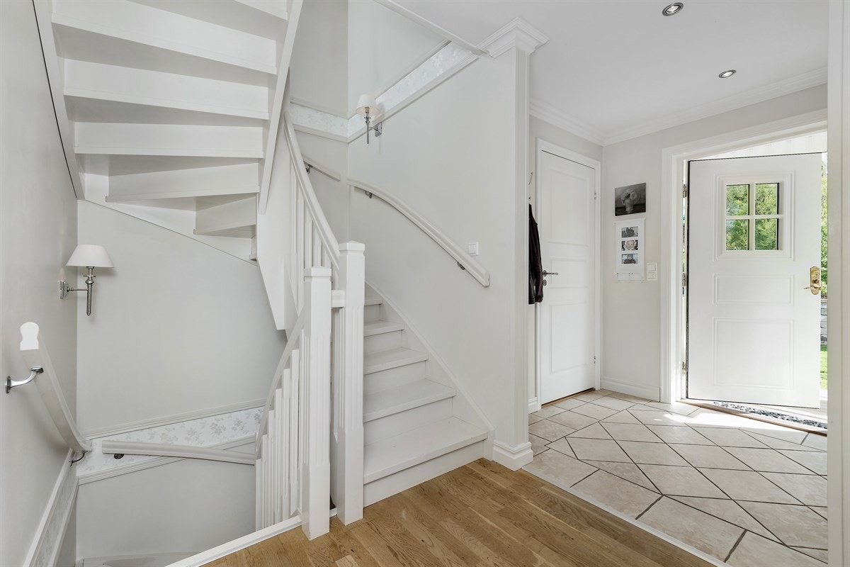 Entreen er innbydende med lyse fliser på gulv og downlights i tak. Rommet er praktisk innredet med garderobeskap og åpen garderobeløsning. Galleribilde