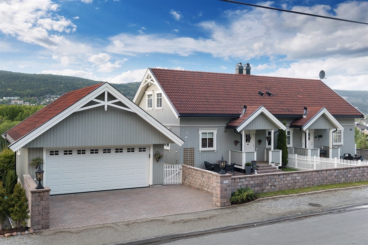 Foran boligen er det bygd opp ett svært stilfullt steingjerde, som rammer inn forhagen med plen og steinbelagt adkomst. Galleribilde