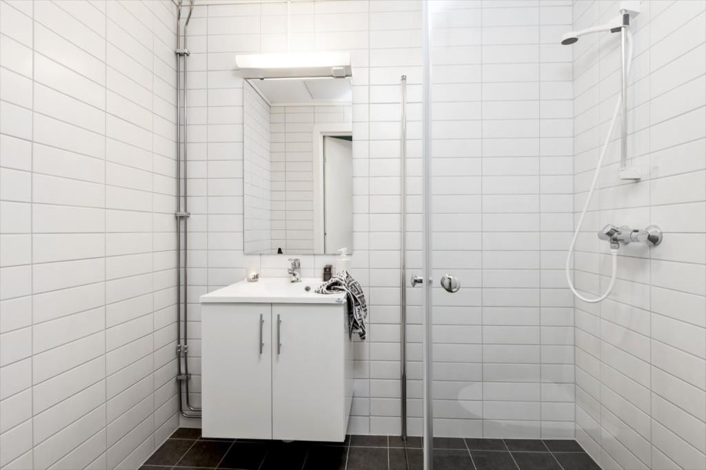 Delikat flislagt bad/wc med dusjhjørne med glassdører, servant med underskap, toalett og varme i gulv Galleribilde