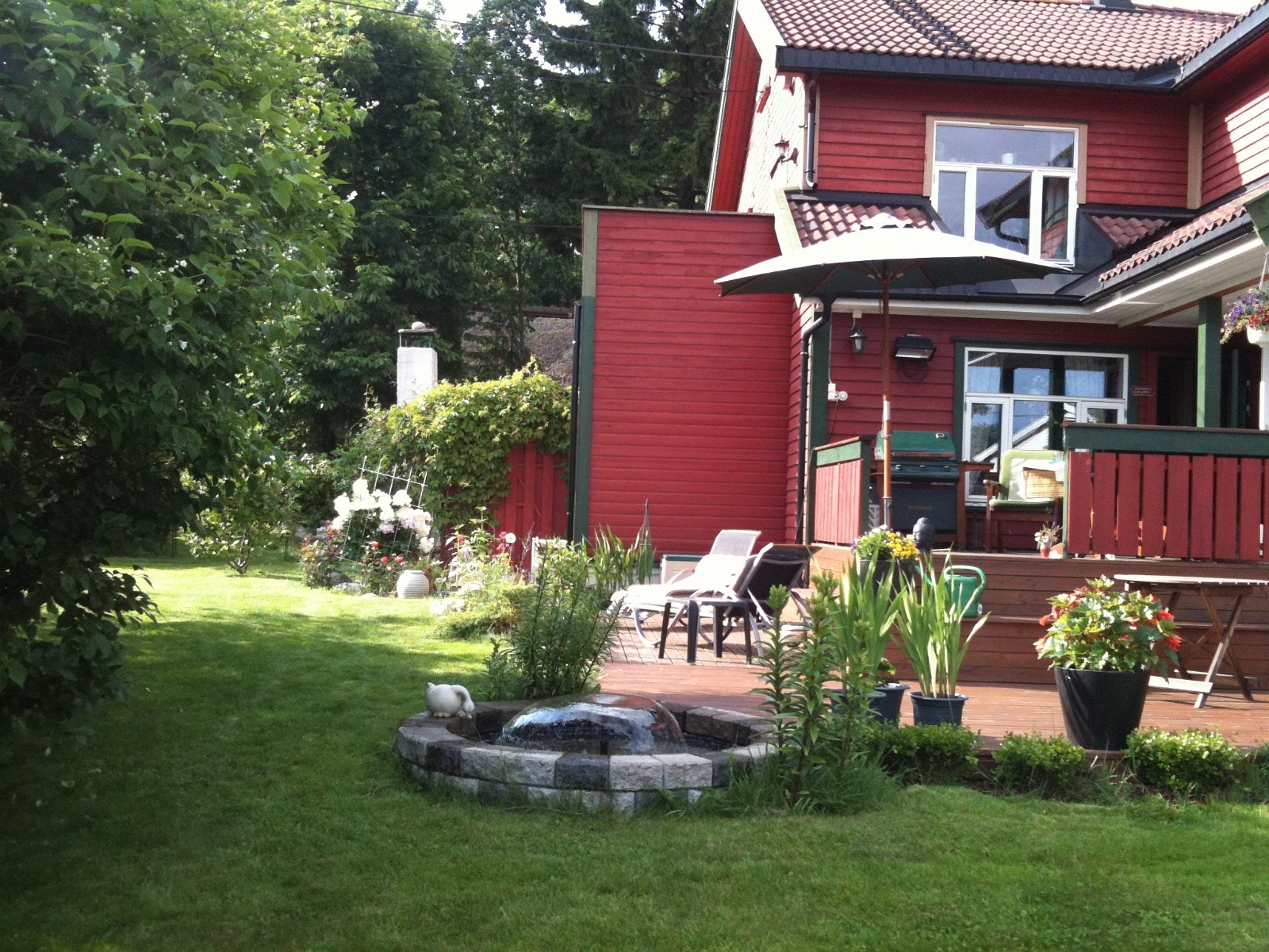 Hage med stauder og fontene i hjørnet av terrassen. Fontenen kan legges lokk over (vinter, ikke i bruk) Galleribilde