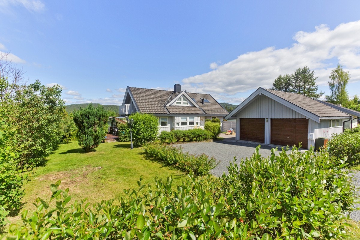 Fasade og hage, med gruset gårsplass og dobbelgarasje. Eneboligen må oppleves, og passer perfekt for en familie. Galleribilde