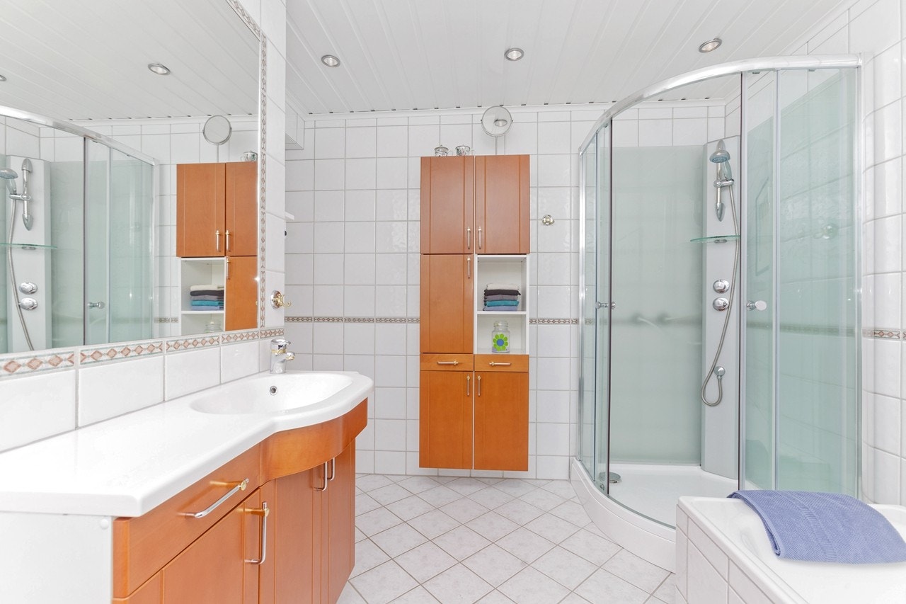 Hovedbad med mye skapplass, dusjkabinett og innmurt speil over servantinnredningen. Galleribilde