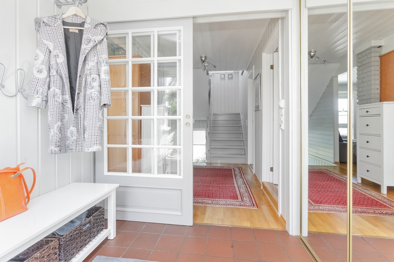 Entré med fliser på gulvet, skyvedørsgarderobe og knagger til yttertøy. Galleribilde