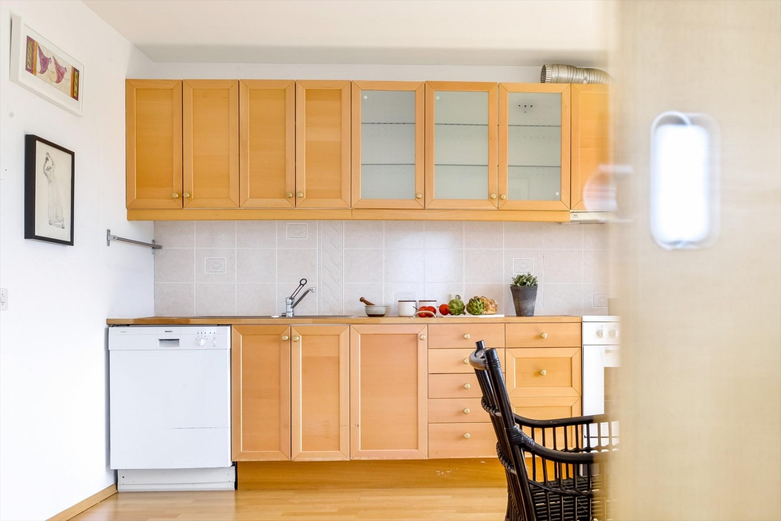 Kjøkkeninnredning praktisk montert på en rekke med profilerte, heltre eikefronter og tre overskapdører med glass Galleribilde