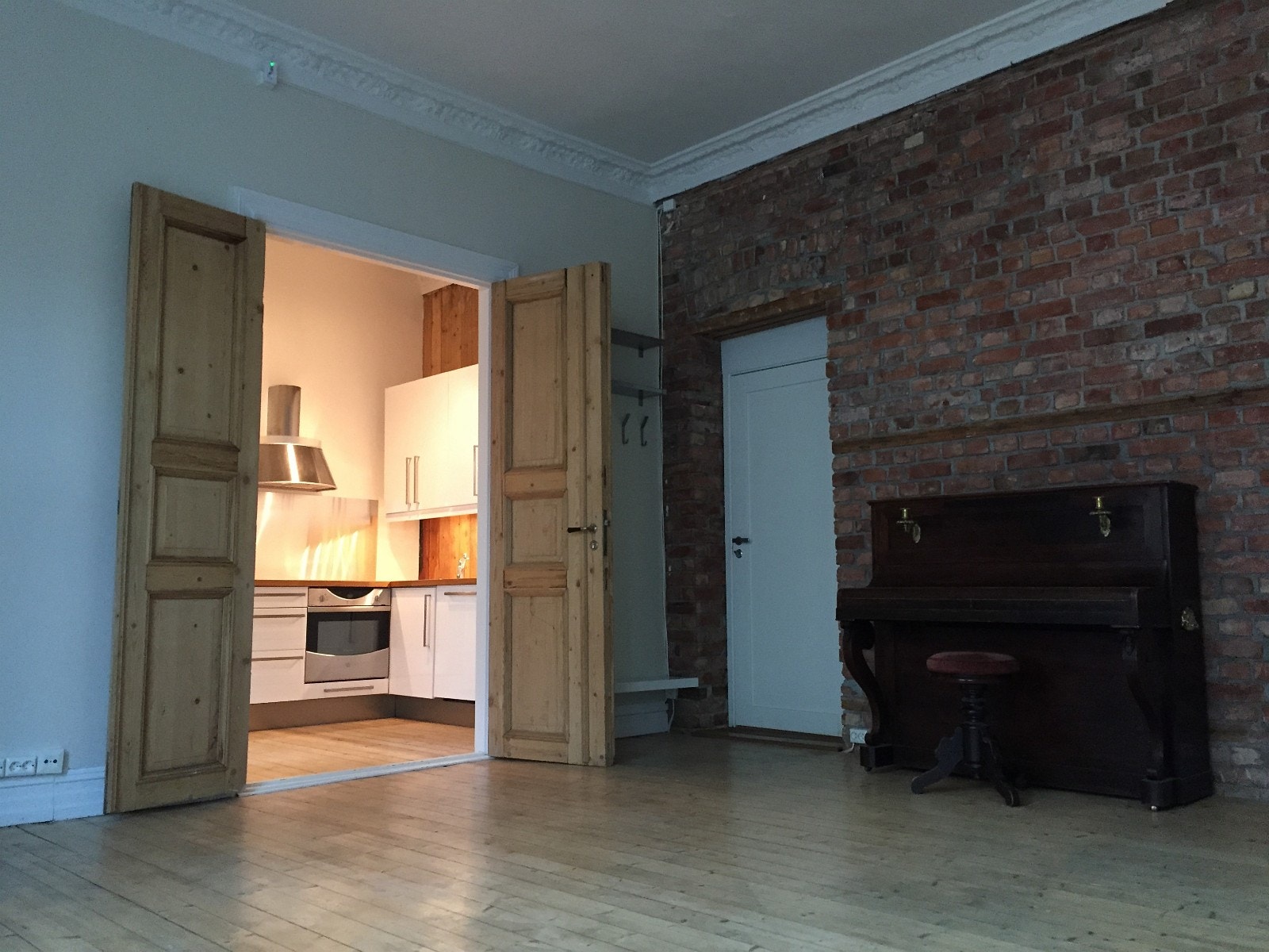 Store, gamle tredører i heltre skiller kjøkken og stue. Pianoet er fjernet fra leiligheten. Galleribilde