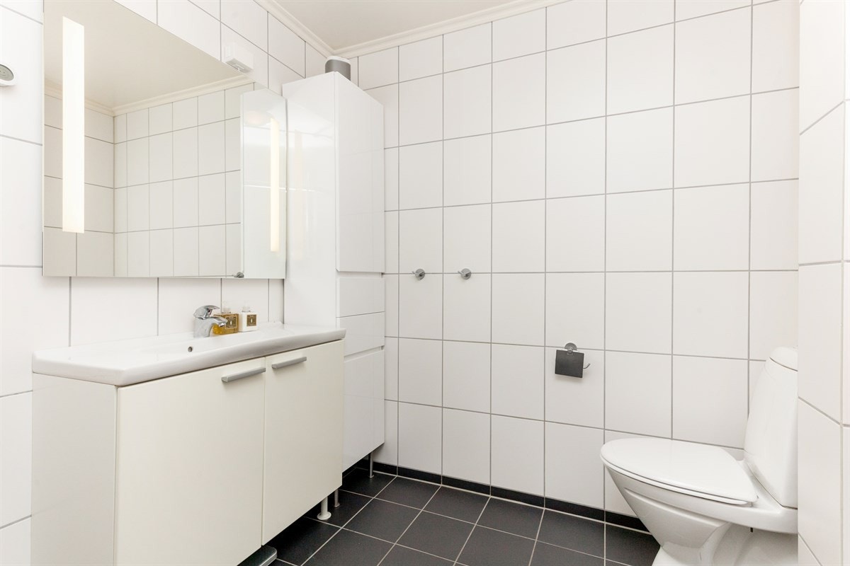Badet er innredet med dusjplass, servant med skapinnredning, speil med belysning og wc. Galleribilde