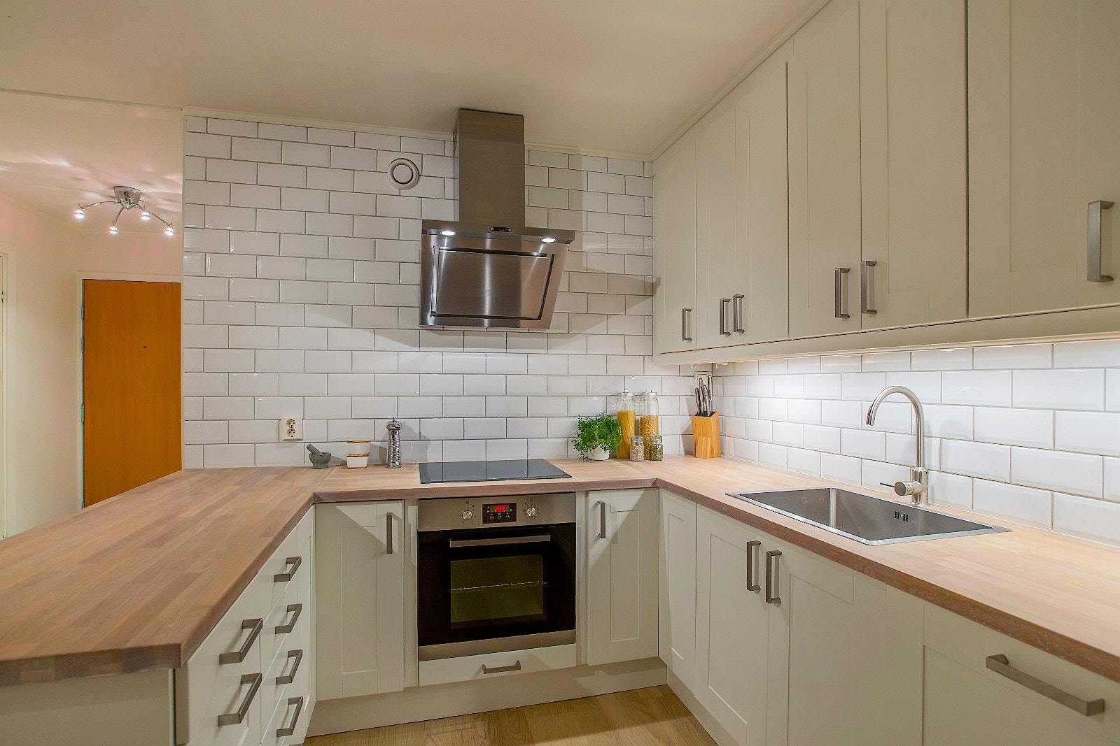 Delikat kjøkken med heltre benkeplate og lys under overskap Galleribilde