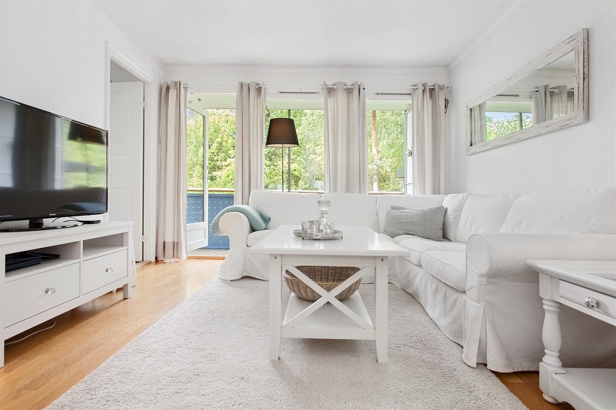 Mye dagslys slipper inn til stuen, som i seg selv har en behagelig lys profil av hvitmalte vegg- og himlingsflater. Galleribilde