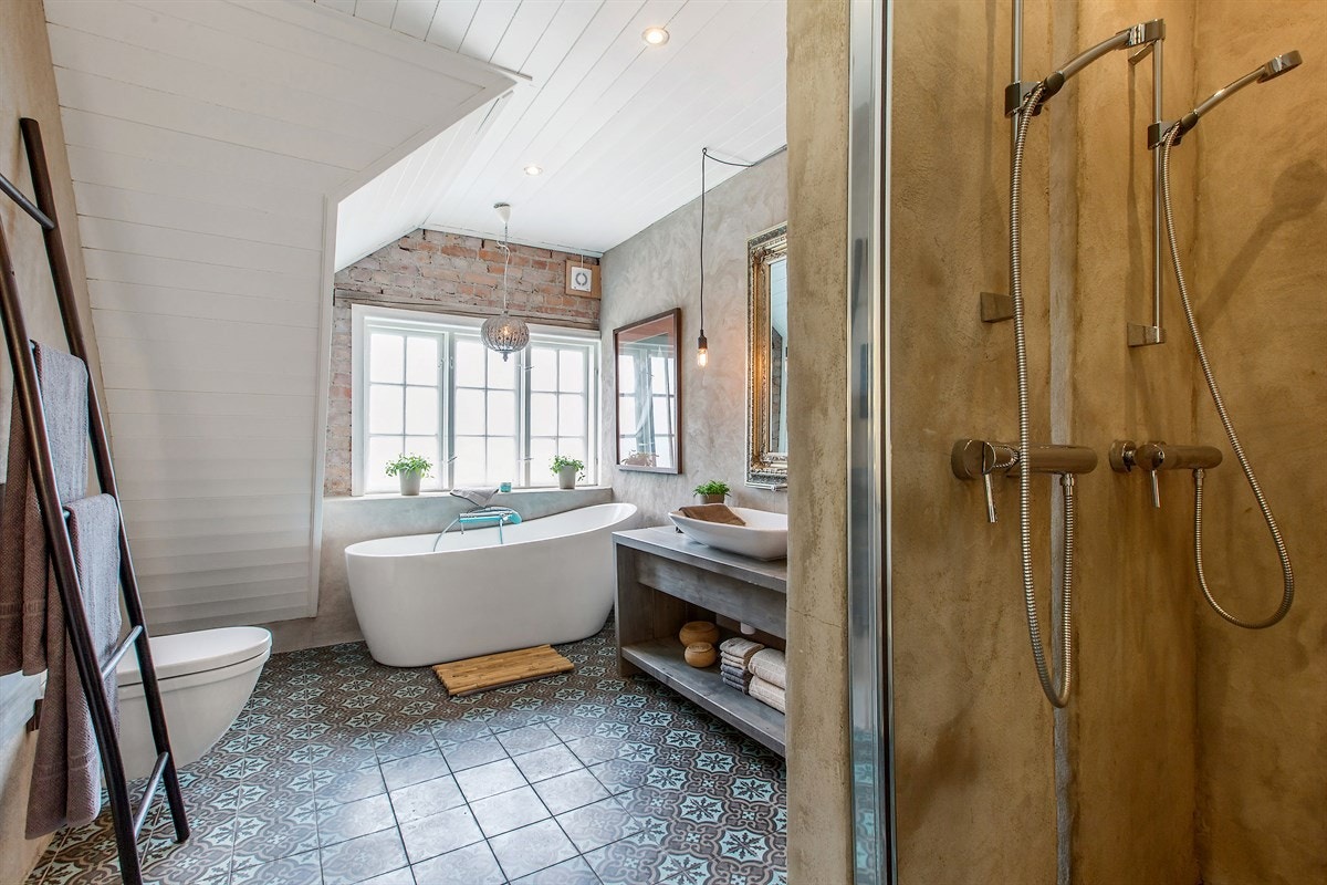 Badet med dobbeldusj, et stort, herskapelig og frittstående badekar og rikelig med boltreplass er et sted for avlappning. Galleribilde