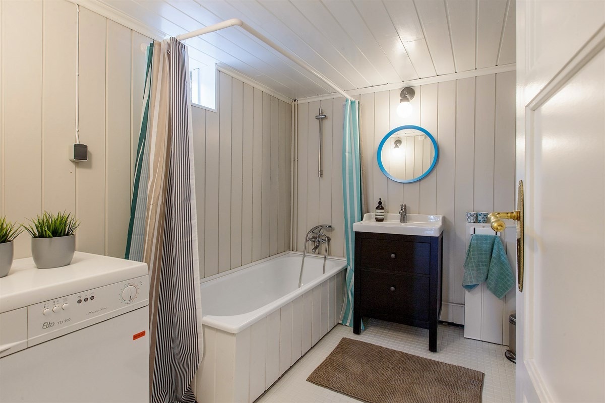 Etasjens bad er av eldre dato og ett av få steder oppussingen aldri rakk frem til. Rommet er av eldre dato, men varmtvannsberederen er fra 2013 og servanten er ny. Plass for vaskemaskin innenfor døren og tørketrommel ved badekaret. Galleribilde