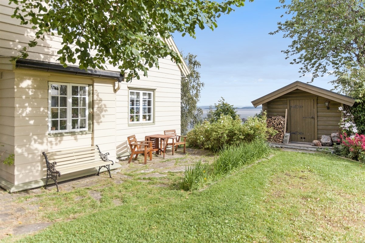 Idyllisk hage med en vakker uteplass på baksiden av huset. Her er det også en praktisk redskapsbod Galleribilde