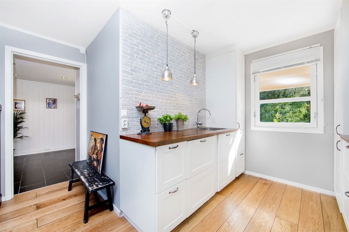 Kjøkkeninnredningen har håndlagde spesialbestilte castle stone fliser over valnøtt benkeplate. Galleribilde