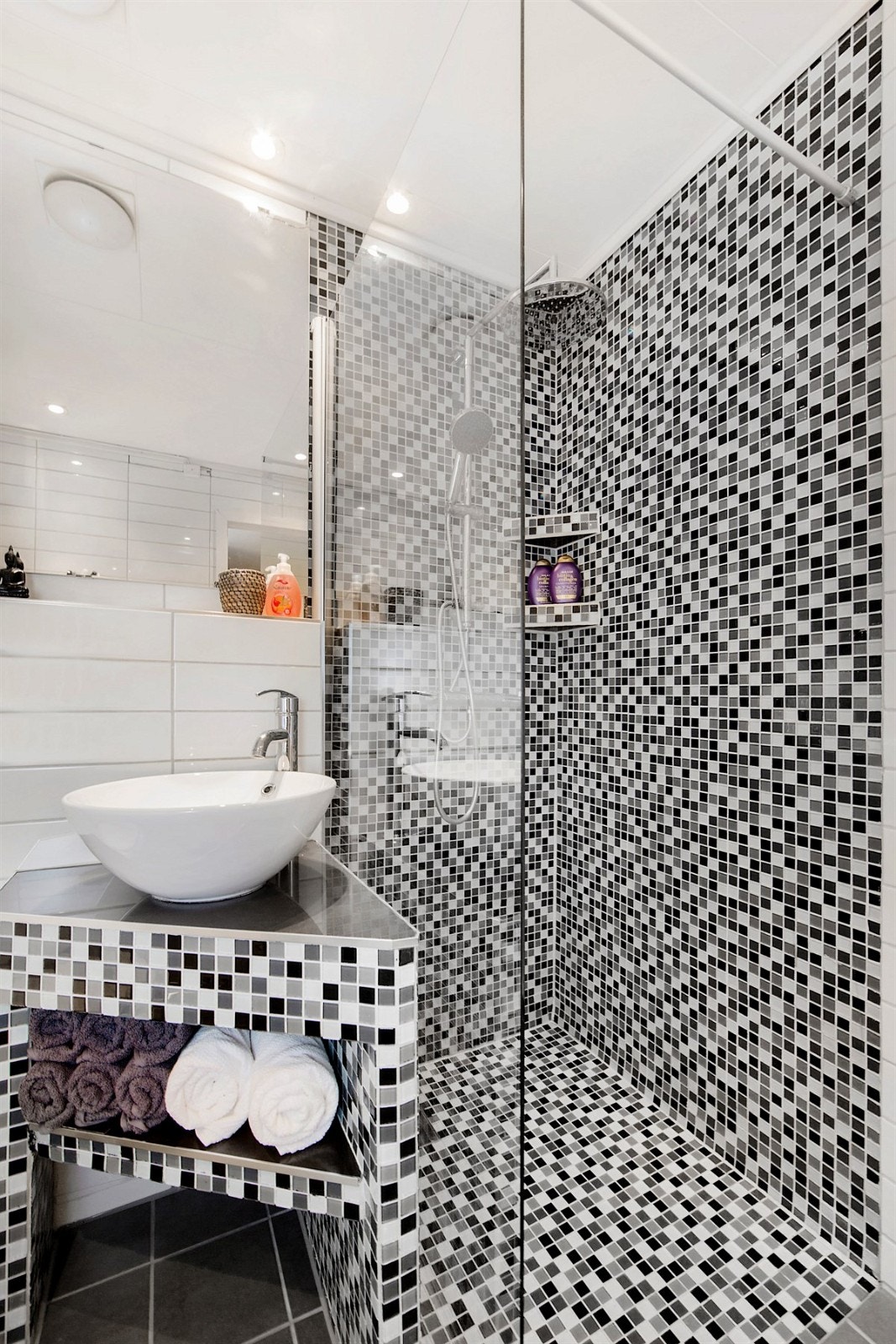 Dusjhjørne med glassvegg, dusjbatteri, dusjutstyr og plastsluk. Det er varme i gulv på badet. Galleribilde