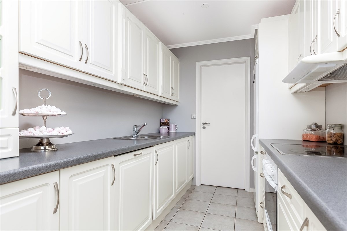 Rikelig med skap- og benkeplass og integrert ovn/koketopp og oppvaskmaskin. Praktisk med inngang til vaskerom. Galleribilde