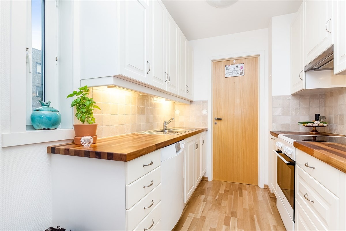 Kjøkkenet har lyse profilerte fronter og heltre benkeplate. Sidevindu slipper ekstra dagslys inn. Inngang til vaskerom. Galleribilde