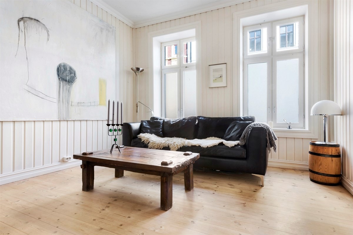 Leiligheten har en romslig og tiltalende stue med ekstra takhøyde, vakker original gipsrosett i taket, og flotte, takhøye vinduer som gir rikelig med lys. Galleribilde