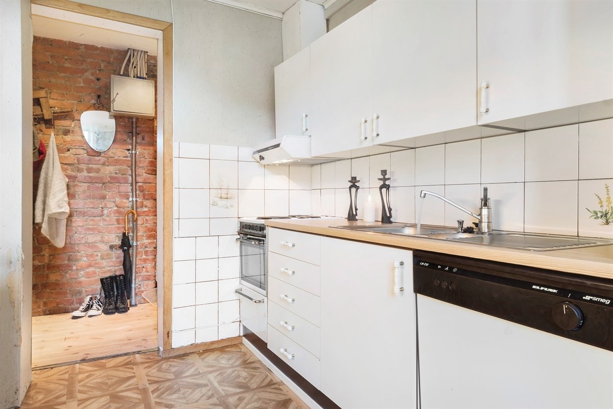 Videre er kjøkkenet utstyrt med frittstående komfyr, oppvaskmaskin og ventilator. Rommet har laminat på gulv, et stort, takhøyt vindu som gir godt med naturlig lys, samt en god, bred vinduskarm som gir en fin sitteplass for å nyte morgenkaffen. Galleribilde