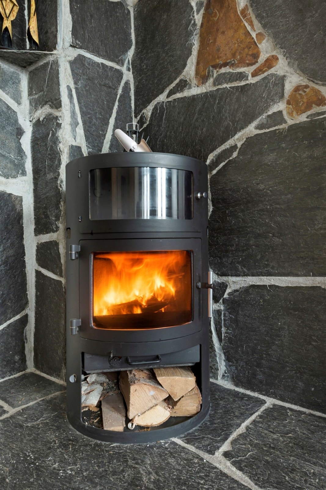 Stilig peisovn i dansk design, for ekstra varme og hygge.
Veggen bak peisovnen er i mørk Oppdalsskifer og den står på støpt betong med skifer Galleribilde