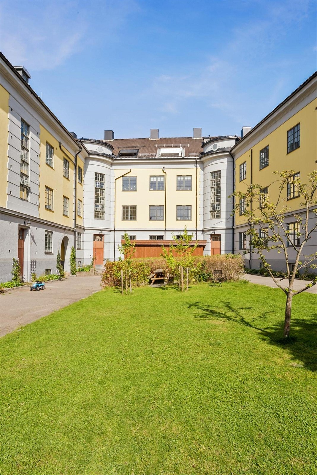 Flott bakgård med gressplen, beplantning, lekeplass og sittegrupper. Galleribilde