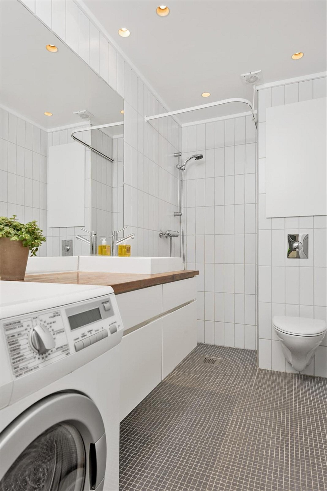 Leiligheten har et innbydende og delikat bad. På gulvet er det pene mosaikkfliser og lyse fliser på vegger. På badet er det vegghengt klosett, spotter i tak, dusjhjørne, servant med skapinnredning, speil, varmekabler i gulv og opplegg for vaskemaskin. Galleribilde