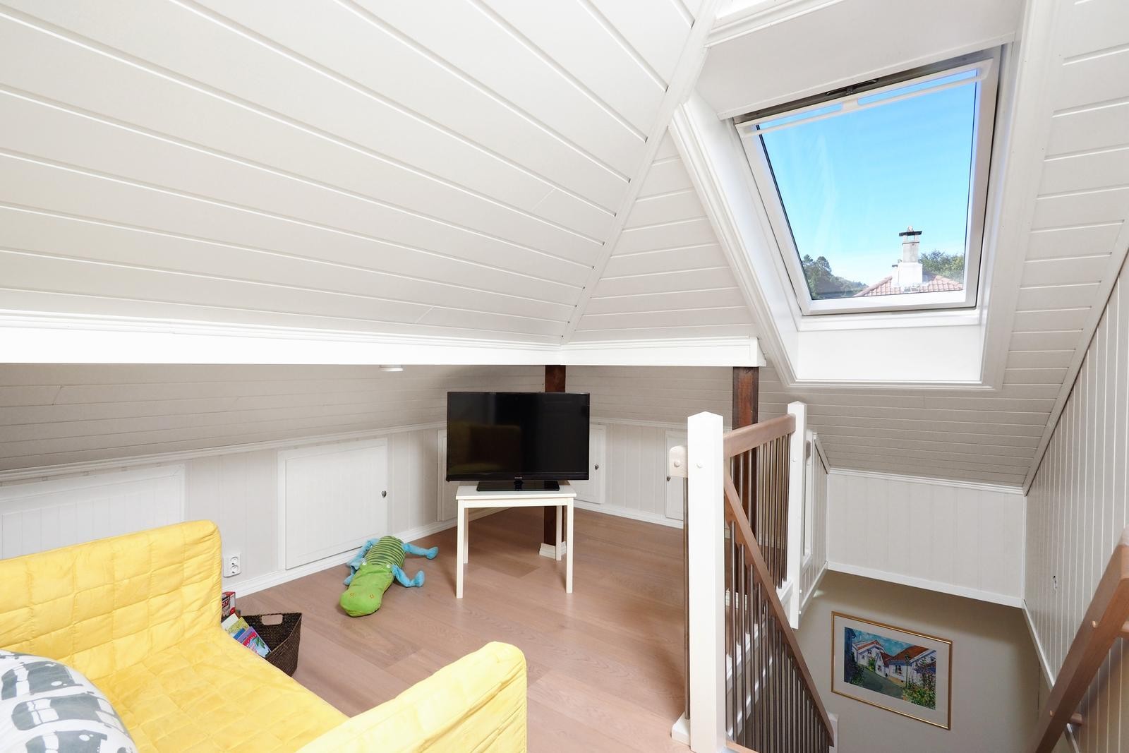 Trappen fra stuen tar deg opp til loftsetasjen hvor du finner et trapperom som i dag er innredet som en koselig tv-stue med plass til sofa og tv. I kneveggen her har man god oppbevaring. Galleribilde