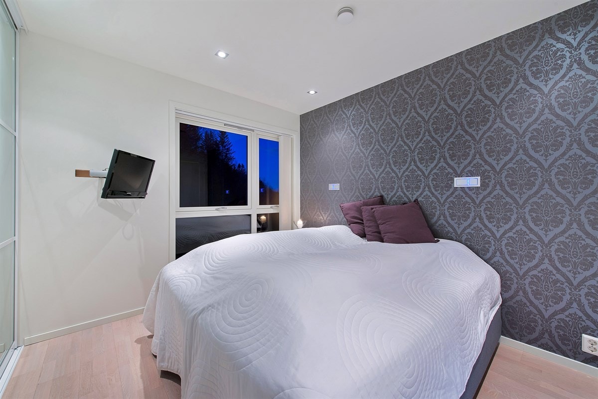 Hovedsoverommet i 1. etasje er på ca. 12m², og har vegghengt TV, innfelte LED designlamper for leselys og en stor skyvedørsgarderobe. Galleribilde