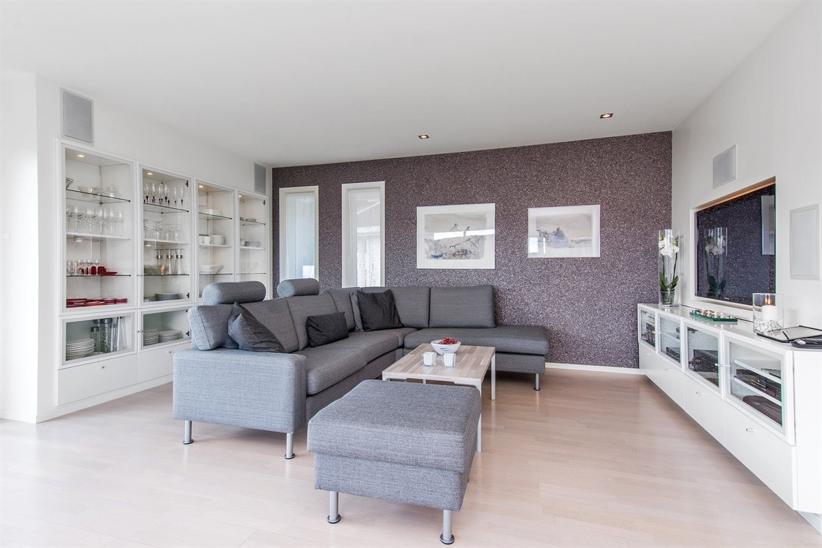 Spesialtilpasset stereobenk og innfelte skap med belysning har hyggelig selskap av en tøff kontrastvegg med designtapet av stein. Galleribilde